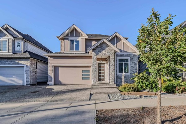 Close-up view of the house entrance with a beige garage door and glass panel front door. - 14215 61b Avenue, Surrey