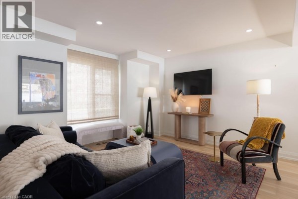 Living room with blue sofa, patterned armchair, rug, and mounted television. - 1422 Ghent Avenue, Burlington