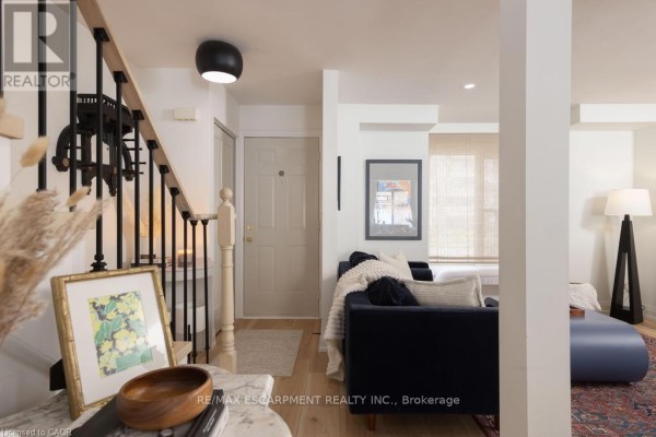 Entryway with a beige door, stairs, and a living room in the background. - 1422 Ghent Avenue E, Burlington