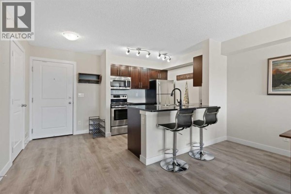 Open concept living area with kitchen island and two bar stools. - 1423, 81 Legacy Boulevard Se, Calgary