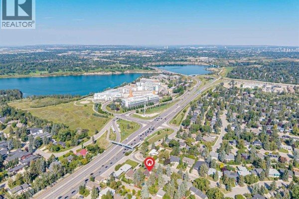 Aerial view of a residential neighborhood with a lake and highway in the background. - 1423 75 Avenue Sw, Calgary