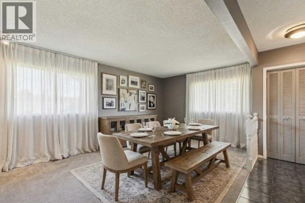 Dining room featuring a wooden table, chairs, a staircase, and stone accent wall. - 1423 75 Avenue Sw, Calgary