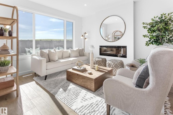 Living room with a white sofa, wood coffee table, fireplace, and large window with natural light. - 1424 Cristall Pl Sw, Edmonton