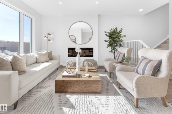 Living room featuring a large window, fireplace, and comfortable seating arrangements. - 1424 Cristall Pl Sw, Edmonton