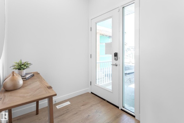 Entrance foyer with a glass door, wooden console table, and decorative vase. - 1424 Cristall Pl Sw, Edmonton
