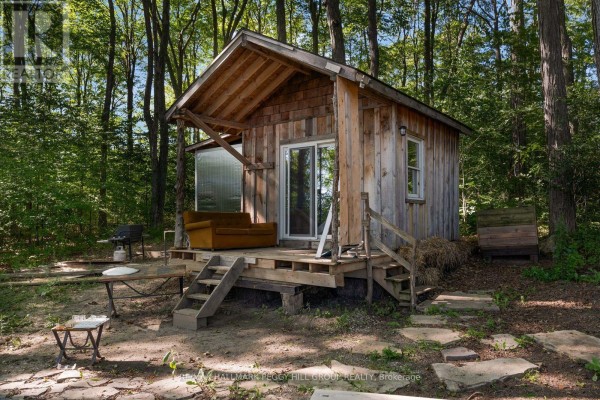 Small wooden cabin in the woods with a covered porch, sliding glass door, and wood exterior. - 1424 Klondike Park Road, Clearview