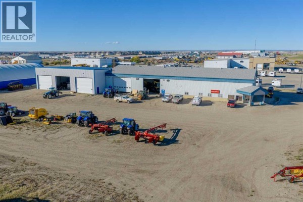 Wide aerial shot of the commercial property showing the building and farm equipment. - 14250 100 Street, Rural Grande Prairie No  1, County Of