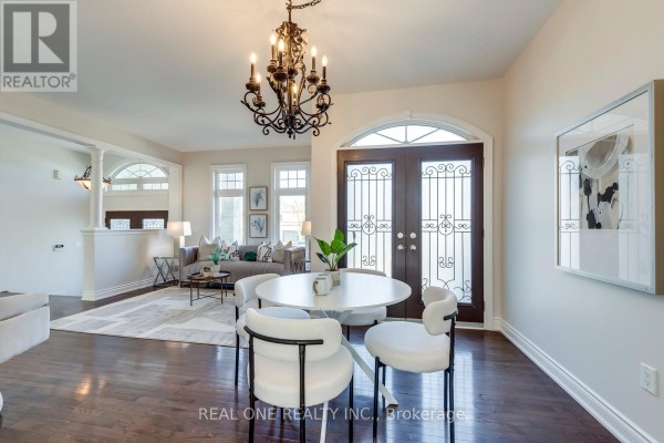 Round dining table, white chairs, ornate chandelier, and double doors with grills - 1426 Redwing Court Oakville