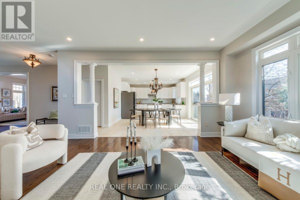Living room with white sofa and armchair, open to dining area and modern kitchen - 1426 Redwing Court Oakville