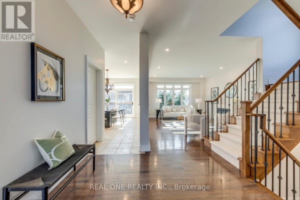 Hallway with hardwood floors, bench, art, and view to living room - 1426 Redwing Court Oakville