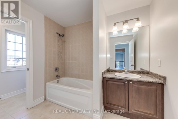 Bathroom with tiled tub/shower, vanity, sink, mirror & window - 1426 Redwing Court Oakville