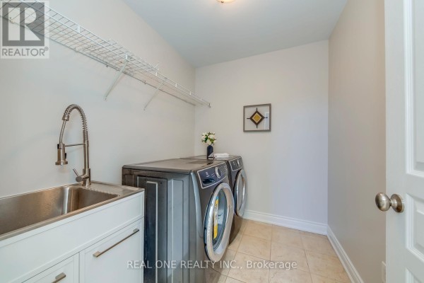 Laundry room with utility sink, washer, dryer, and shelving - 1426 Redwing Court Oakville