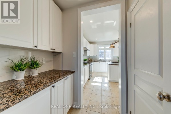 Kitchen with white cabinets, granite countertops, and tile flooring - 1426 Redwing Court Oakville