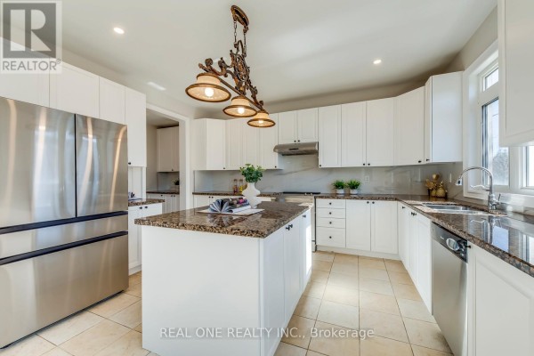 Modern kitchen with island, granite counters, white cabinets, and stainless steel fridge - 1426 Redwing Court Oakville