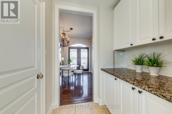 Hallway with white cabinets and granite counter, view into dining area with chandelier and double doors - 1426 Redwing Court Oakville