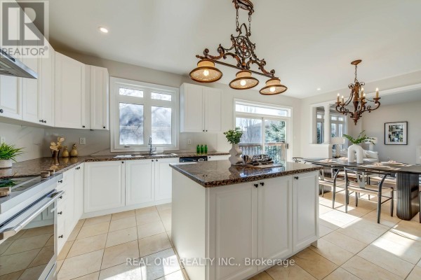 Kitchen with island, granite counters, white cabinets, and dining area - 1426 Redwing Court Oakville