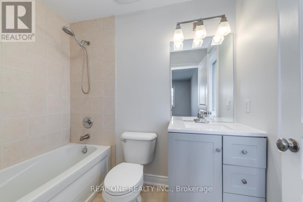 Modern bathroom with gray vanity, white tub, and tiled shower walls - 1426 Redwing Court Oakville