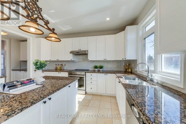 Kitchen with granite countertops, white cabinets, island, and stainless steel appliances - 1426 Redwing Court Oakville