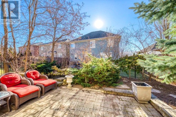 Wicker patio furniture on stone patio with pond and garden - 1426 Redwing Court Oakville