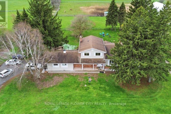 Close-up view of the rear exterior of a house with a large deck and sliding glass doors. - 14264 Eighth Line, Halton Hills