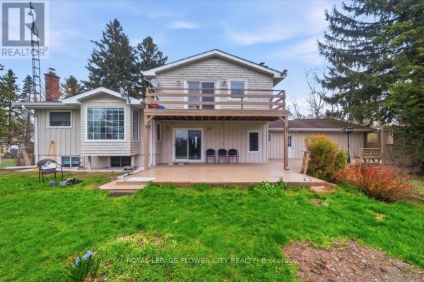 Wooden deck with railings and outdoor lighting, adjacent to a light beige sided structure. - 14264 Eighth Line, Halton Hills