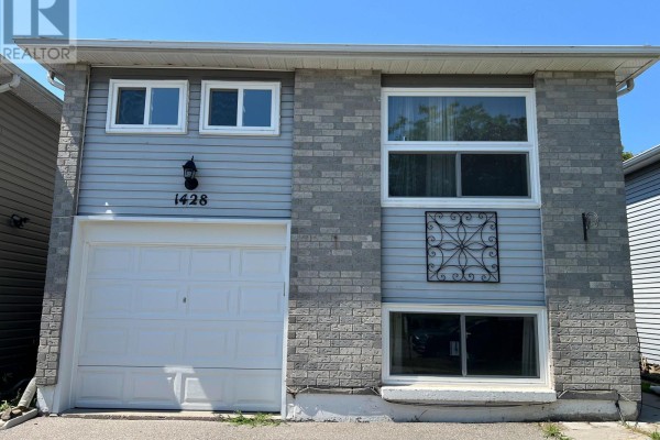 Open-concept living area with light wood floors, white walls, and a dark sofa. - 1428 Outlet Drive, Oshawa