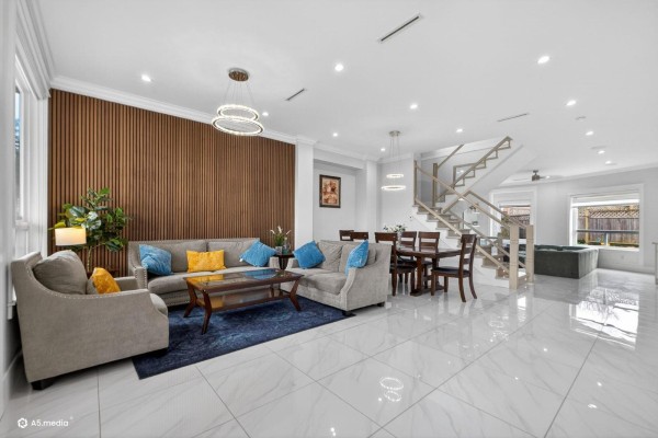 Open living area with modern decor, large windows, and dining space featuring a staircase. - 14298 62 Avenue, Surrey