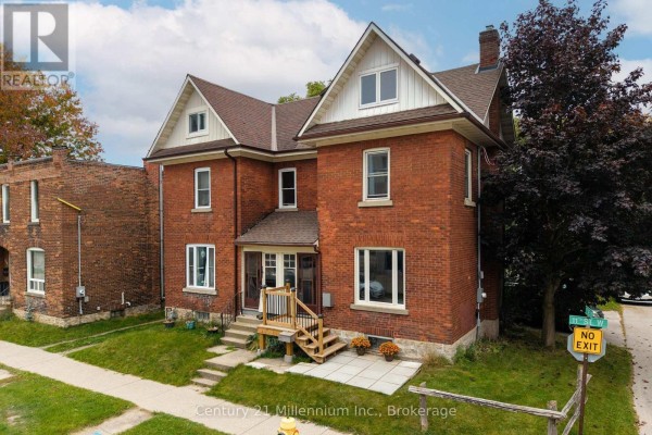 Front exterior of the red brick semi-detached home with a covered porch and wooden stairs. - 143 11th Street W, Owen Sound