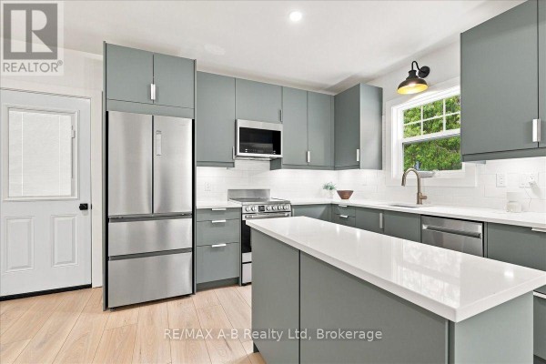 Modern kitchen with grey cabinets, stainless steel appliances, and island - 143 Britannia Street Stratford
