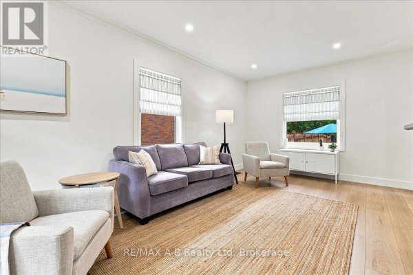 Living room with a grey sectional sofa, two armchairs, and a jute rug. - 143 Britannia Street, Stratford