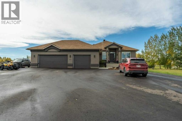 Wide shot of the property exterior showing the house, driveway, and surrounding landscape. - 143 Crocus Ridge Drive, Rural Rocky View County