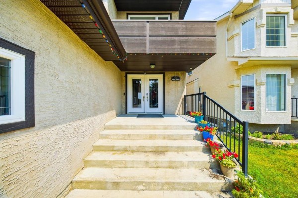 Front entrance stairs and double doors of a modern house with potted flowers. - 143 Mosselle Drive, Winnipeg