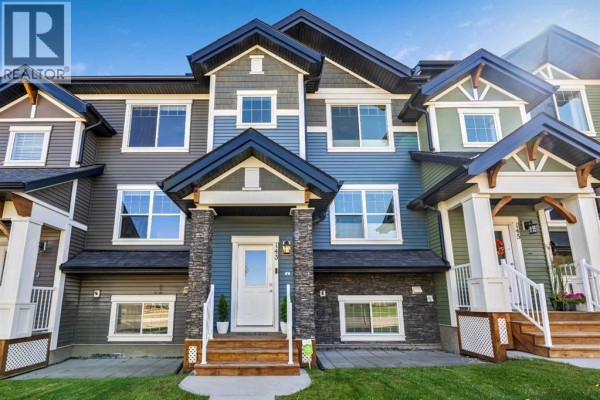 Exterior view of a modern townhouse with blue siding and stone accents. - 143 Nolan Hill Boulevard Nw, Calgary