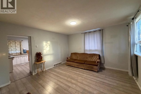 Living room with view into a kitchen, featuring a brown sofa and light grey walls. - 143 Sixth Avenue N, Yorkton