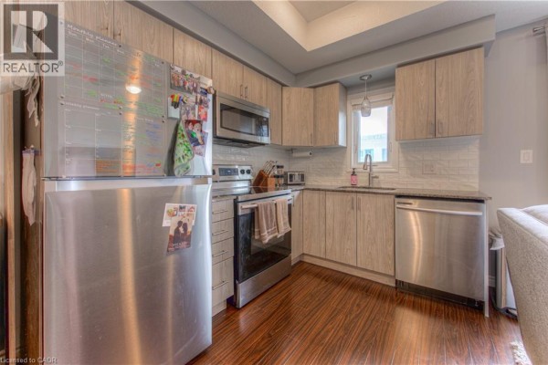 Kitchen with stainless steel appliances, light wood cabinets, and dark wood floor. - 1430 Highland Road W Unit# 19a, Kitchener