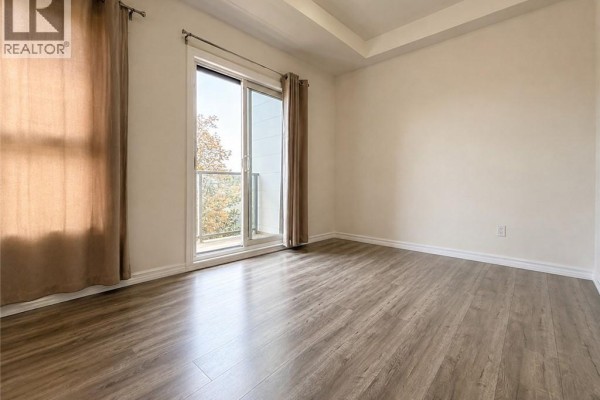 Bedroom with sliding glass door, beige curtains, and neutral walls. - 1430 Highland Road W Unit# 36b, Kitchener