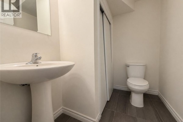 Powder room with pedestal sink, toilet, and tiled floor. - 1430 Highland Road W Unit# 36b, Kitchener