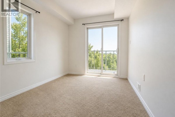 Empty bedroom with beige carpet, window, and sliding glass door. - 1430 Highland Road W Unit# 36b, Kitchener