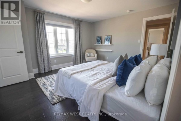 Primary bedroom with a king-size bed, dark wood floors, a patterned rug, and a large window. - 1430 Simpkin Road, Innisfil