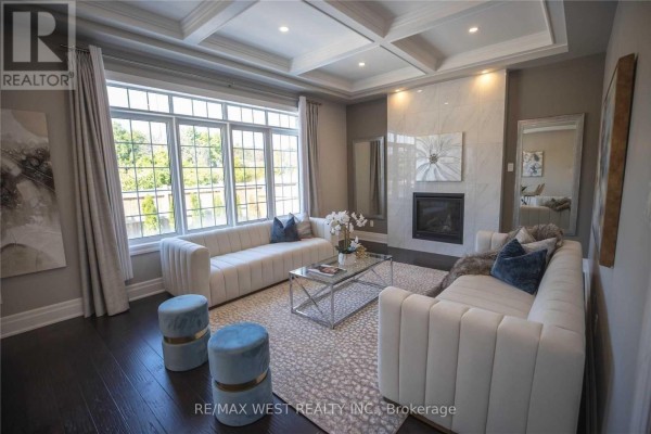 Living room with a fireplace, large windows, coffered ceiling, white couches, and a glass coffee table. - 1430 Simpkin Road, Innisfil