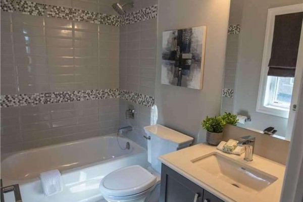 Bathroom with a bathtub, shower, vanity with a white countertop, and grey tiled walls. - 1430 Simpkin Road, Innisfil