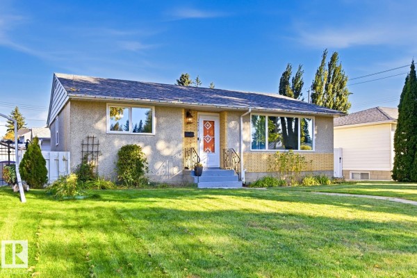 A slightly angled front view of the house showing the lawn, walkway, and landscaping. - 14312 89a Av Nw, Edmonton