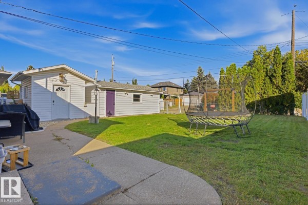 The backyard of the property features a detached garage, lawn, and trampoline. - 14312 89a Av Nw, Edmonton