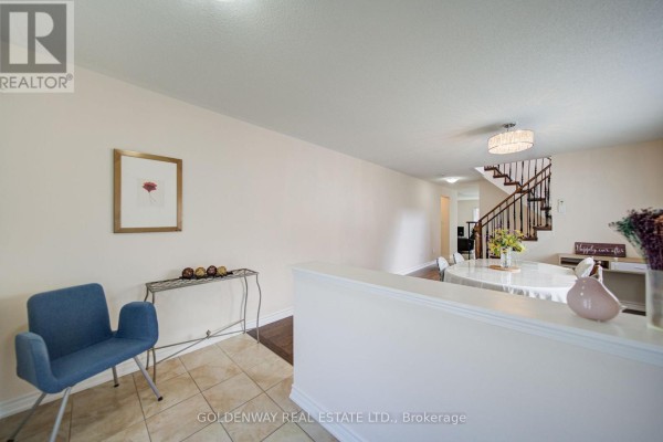 Interior view of a living space with a blue armchair, console table, and dining area. - 1433 Rennie Street, Oshawa