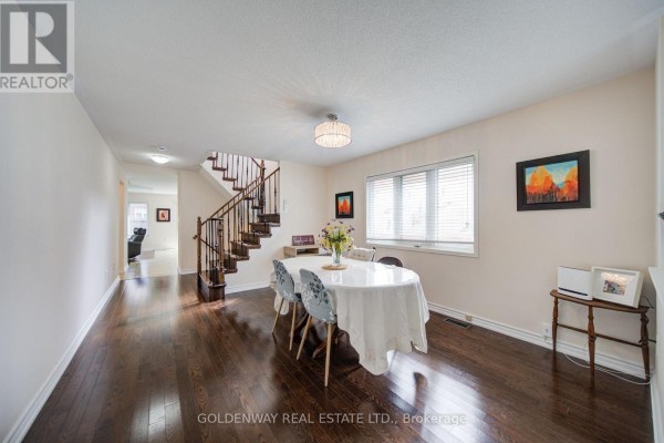 Interior view of a dining room with a round table, dark wood floors, and a staircase. - 1433 Rennie Street, Oshawa