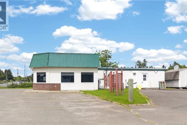 Side view of the commercial building with a green roof, white siding, and a small shed. - 1434 Principale, Neguac