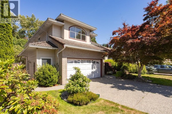Side view of a house showing the entrance, garage, and manicured landscaping. - 1437 Lambert Way, Coquitlam