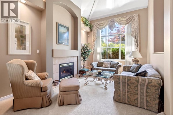 Living room with a fireplace, sofas, armchair, ottoman, and large window. - 1437 Lambert Way, Coquitlam