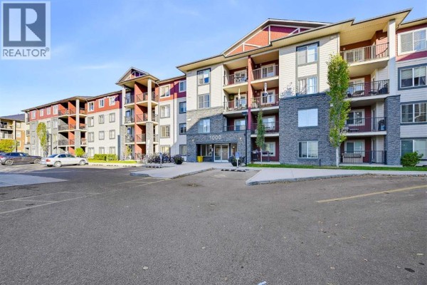Side view of the apartment building showing multiple levels with balconies, windows, and surrounding parking areas. - 1438, 81 Legacy Boulevard Se, Calgary