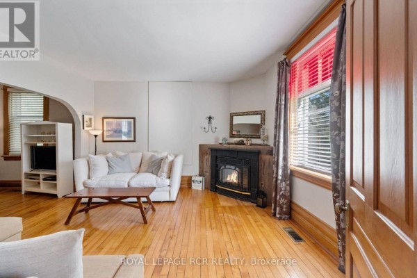 Living room with light wood floors, a white sofa, fireplace, and large window. - 1438 Concession 3 Road, Adjala Tosorontio